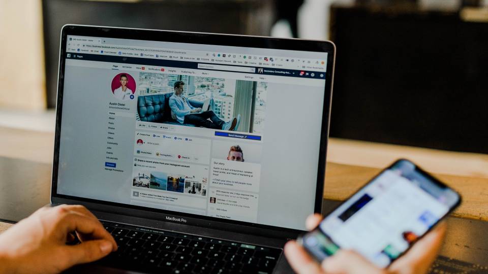 Persona trabajando en su laptop, mientras ve su business page en Facebook preparando ads